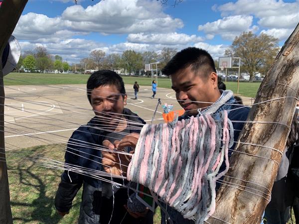 Students engaging in outdoor visual art project with yarn